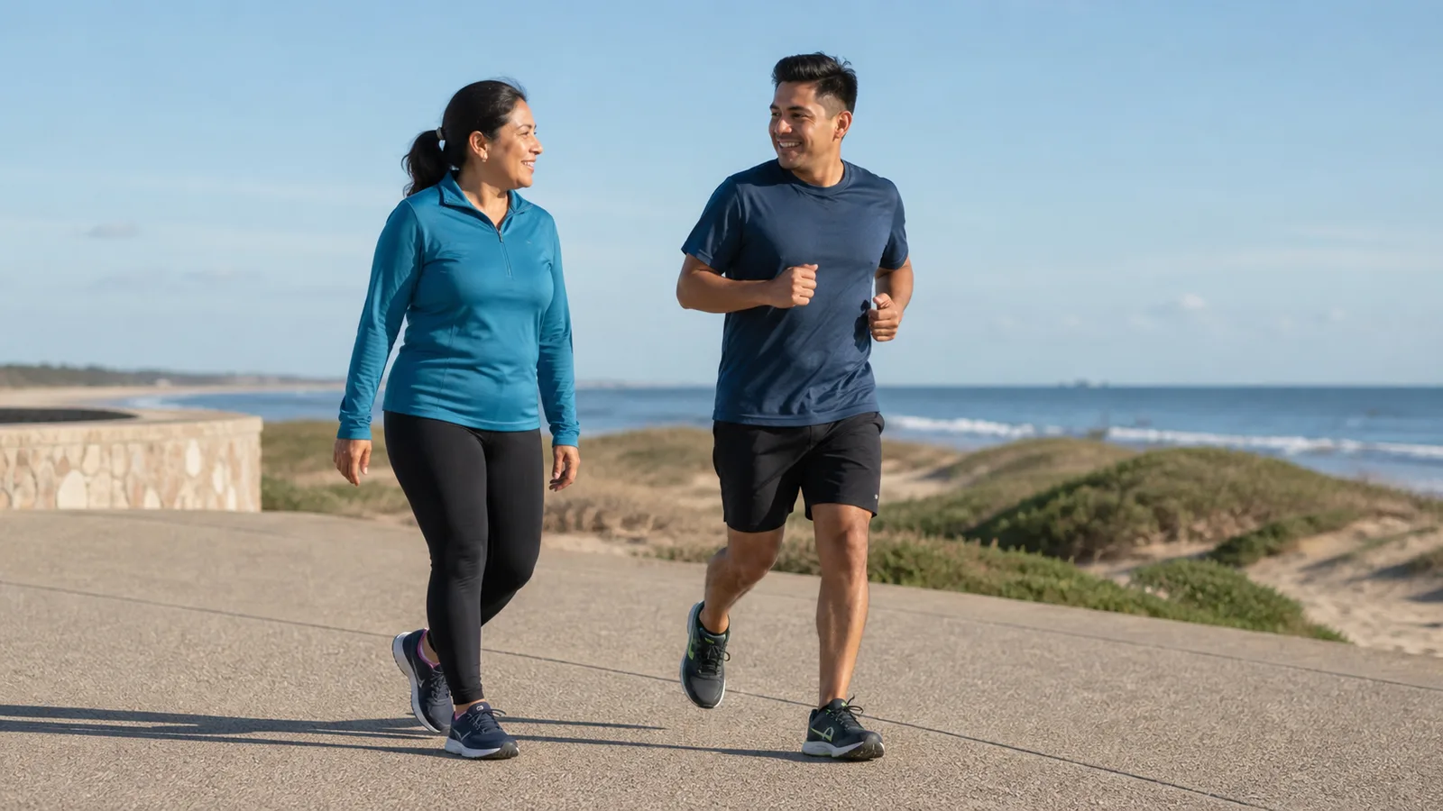 Dos personas alternan caminata y trote suave por un paseo costero de Miramar